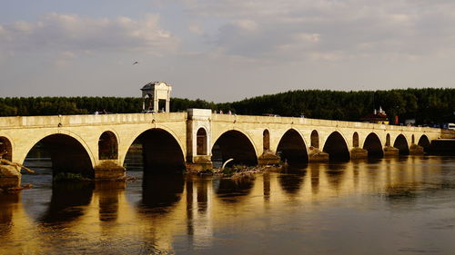 Arch bridge over river against sky
