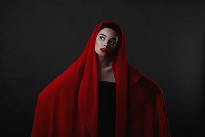 Portrait of woman standing against black background