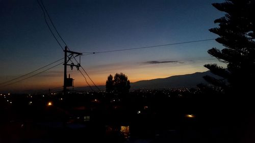 Silhouette of electricity pylon at night