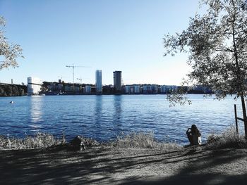 Rear view of man by river against sky