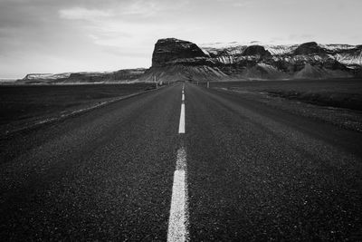 Empty road amidst land against sky