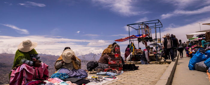 Rear view of people sitting on clothesline against sky