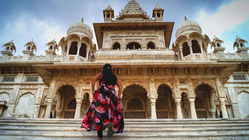 Rear view of woman moving up on steps leading towards historic building