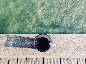 Directly above view of fresh drink on pier over sea