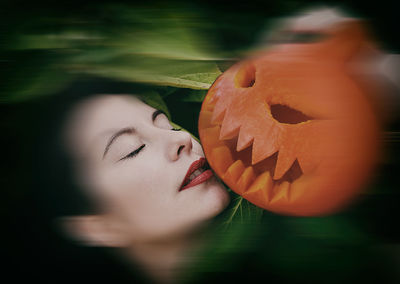 Close-up portrait of woman with pumpkin against blurred background