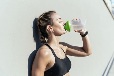 Woman drinking water from bottle on sunny day