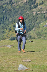 A excited young male traveler smiling walking up in the mountain after finished paragliding flight