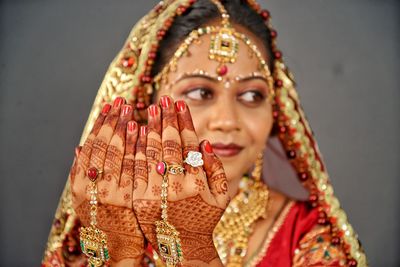 Close-up of smiling bride gesturing while looking away against wall