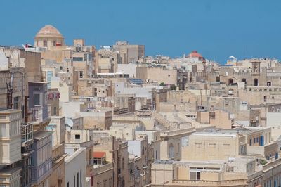 Buildings in city against clear blue sky