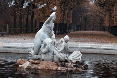 Statue by lake against trees