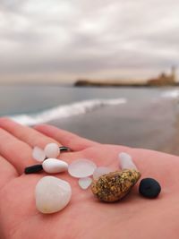 Close-up of hand holding ice cream over sea against sky