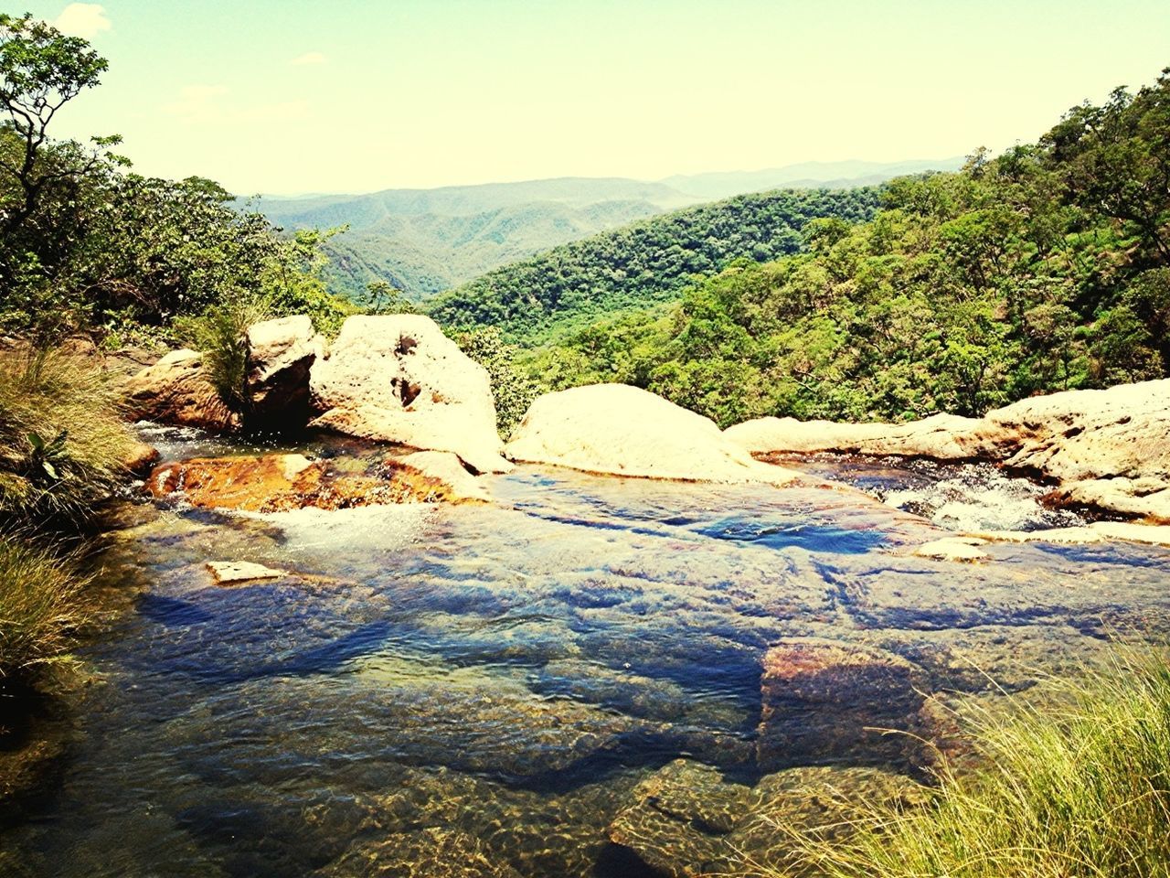 mountain, tranquil scene, tranquility, tree, scenics, beauty in nature, clear sky, nature, landscape, rock formation, rock - object, non-urban scene, plant, growth, mountain range, water, sky, idyllic, sunlight, hill