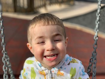 Portrait of smiling boy on swing at playground