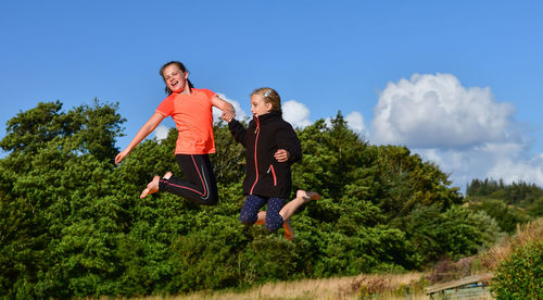 Low angle view of girl jumping against trees