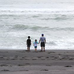 Rear view of men walking on beach