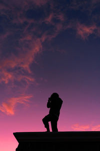 Silhouette man standing on roof against sky during sunset