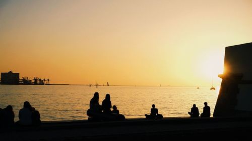 Silhouette of people on sea during sunset