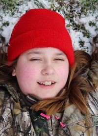 Portrait of smiling girl relaxing on snow field during winter