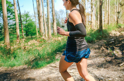 Full length side view of man running on road in forest