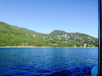 Scenic view of sea and mountains against clear blue sky