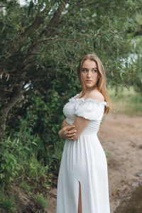 Portrait of young woman standing against plants