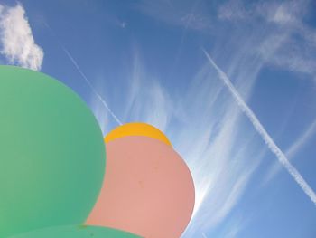 Low angle view of balloons against vapor trails in sky