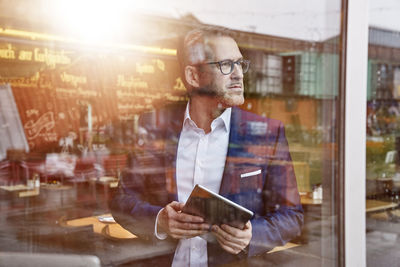 Mature businessman in cafe holding tablet