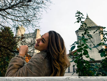 Low angle view of young woman against building