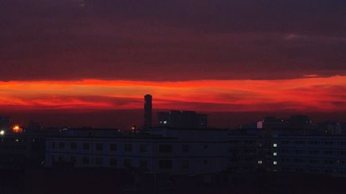 Illuminated factory against sky at sunset