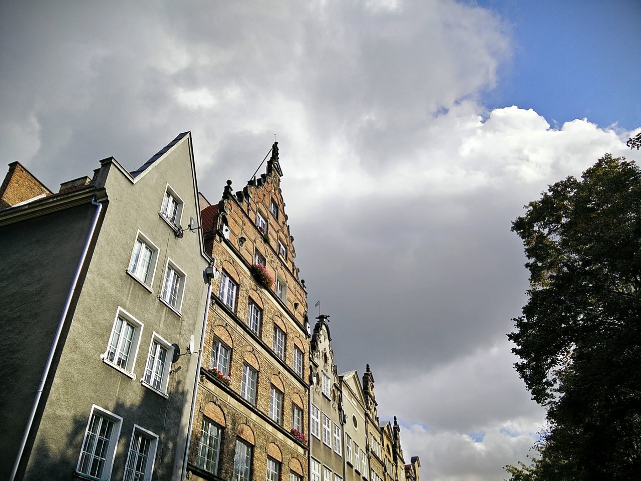 building exterior, architecture, built structure, low angle view, sky, window, cloud, city, cloud - sky, building, outdoors, day, cloudy, facade, tall - high, no people, city life, high section, cloudscape, spire, historic building, cumulus cloud, building story