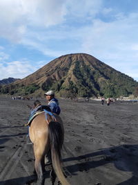 Man riding horse on land against sky