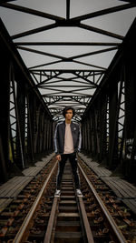 Full length portrait of man standing on railroad tracks