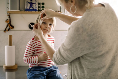 Mother applying bandage on daughter's face at home