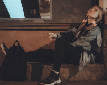 Woman looking at camera while sitting on the street