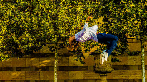 Rear view of man jumping against plants