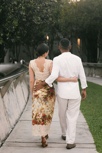 Rear view of couple walking on boardwalk