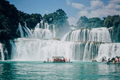 People in boat against waterfall