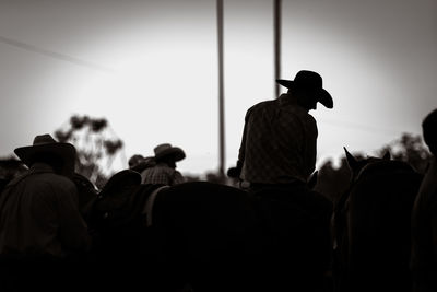 Rear view of silhouette man riding horse against sky