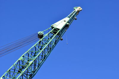 Low angle view of cranes against clear blue sky