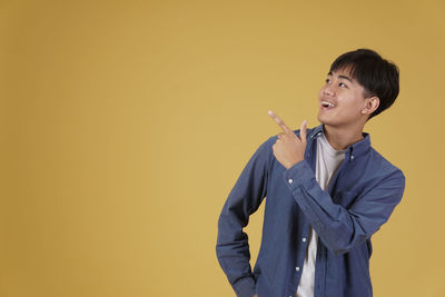 Man looking away while standing against yellow background