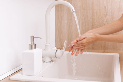 Cropped hand washing hands in sink