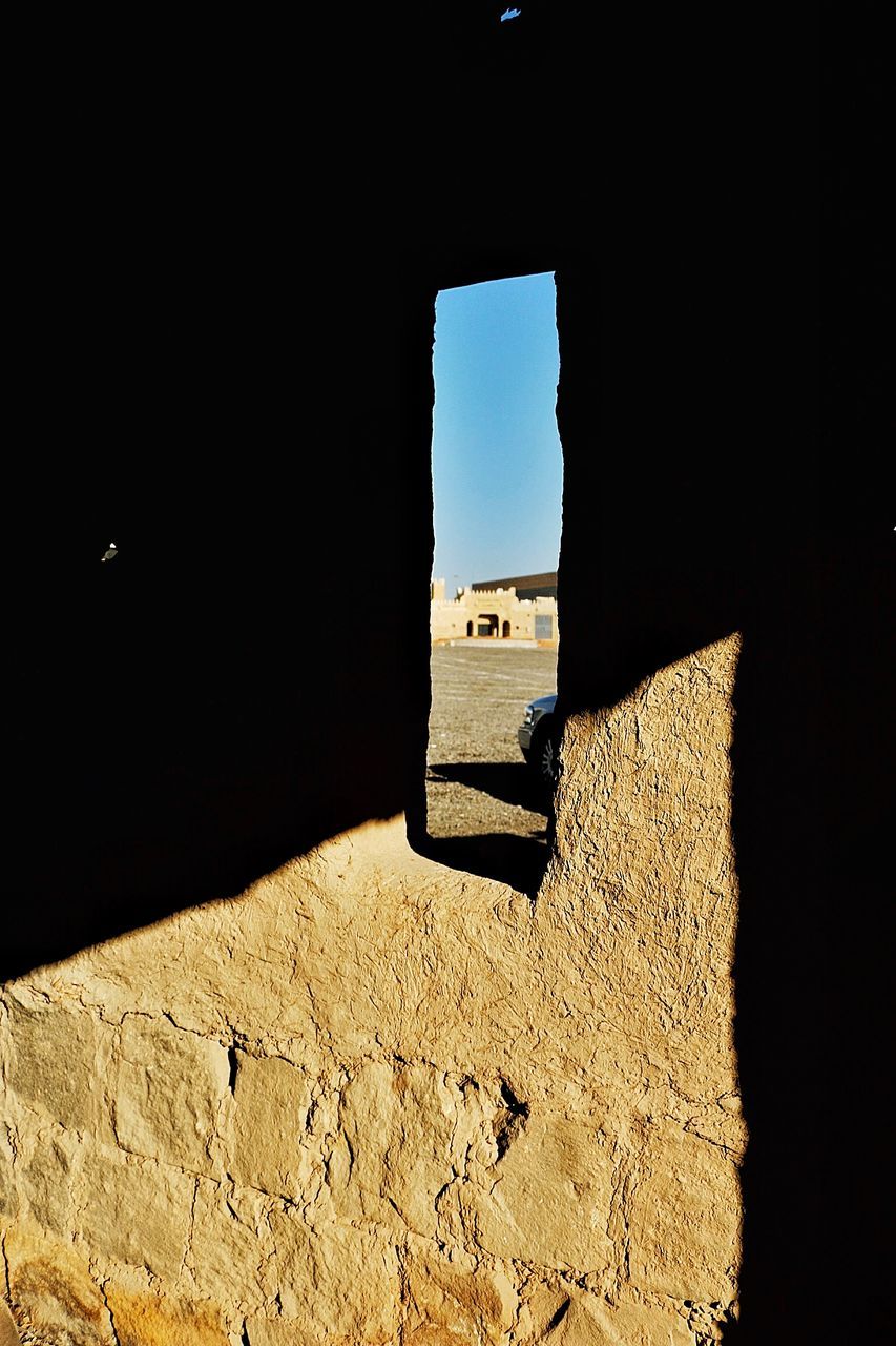 built structure, architecture, indoors, sunlight, clear sky, copy space, window, building exterior, shadow, day, no people, sand, absence, wall - building feature, house, sky, dark, empty, sea, wall