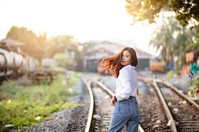 Portrait of woman standing on railroad track against sky