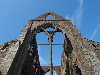 Low angle view of old ruin building against blue sky