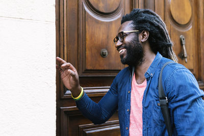 Cheerful young man standing by door in city