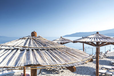 Parasols by sea against clear blue sky