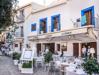 People on sidewalk cafe by buildings in city