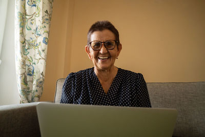 Smiling senior woman sitting at home office workplace looking in laptop.