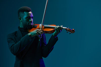 Young man playing violin against clear sky