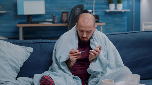 Full length of man sitting on bed